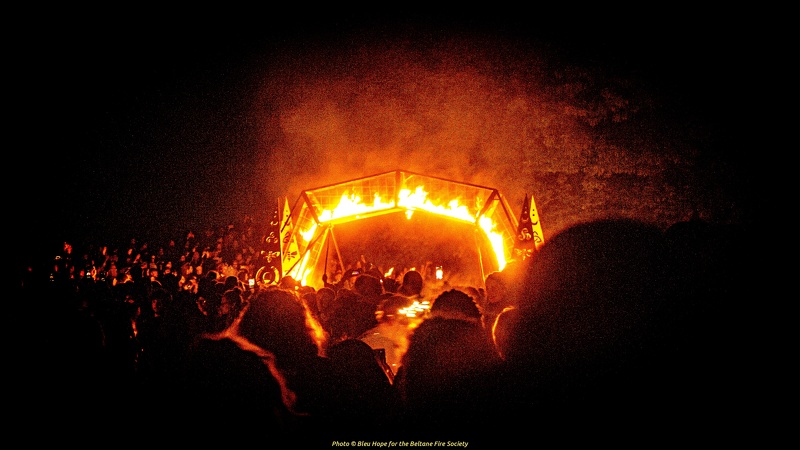 image of a metal arch on fire with crowds surrounding.